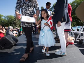Rayna Abraham, 4, smiles after getting her citizenship certificate with her mother, Tiny Abraham, during Canada Day festivities at the Alberta Legislature, in Edmonton July 1, 2016.