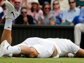 In this  file photo, Roger Federer lies on the court after falling during his men's semifinal singles match at the Wimbledon Tennis Championships in London.