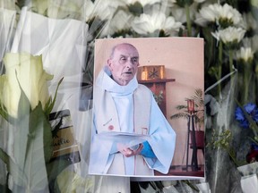 A picture of late Father Jacques Hamel is placed on flowers at the makeshift memorial in front of the city hall closed to the church where an hostage taking left a priest dead the day before in Saint-Etienne-du-Rouvray, Normandy, France, Wednesday, July 27, 2016.