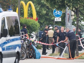 Police stand at a the crime scene where a shooting took place in front of a fast food restaurant in Munich. Nine people died in the mass shooting on Friday.