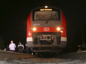 Police officers stand beside a train in Wuerzburg, southern Germany, Monday evening, July 18, 2016, after a 17-year-old Afghan armed with an ax and a knife attacked passengers