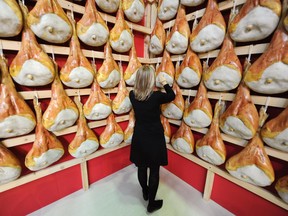 A visitor inspects hams hanging in a stand in Turin