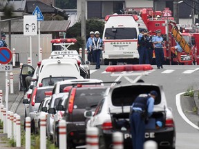 Police officers stand by with ambulances and firetrucks seen on a street near a facility for the handicapped where a number of people were killed and dozens injured in a knife attack Tuesday, July 26, 2016, in Sagamihara, outside Tokyo.