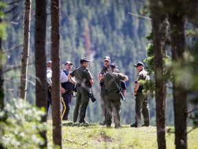 Alberta Fish and Wildlife and RCMP chat near Trapper's Hill Lodges northeast of Cochrane, Alta., after a woman suffered non-life-threatening injuries when she was attacked by a grizzly bear on Tuesday, July 19, 2016.