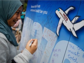 A Malaysian woman writes well wishes on a wall of hope during a remembrance event for the ill fated Malaysia Airlines Flight 370 in Kuala Lumpur, Malaysia, Sunday, March 6, 2016. The search for MH370 may now be suspended—possibly forever