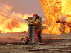 Oil workers and firemen try to extinguish flames at the Khabbaz oil field some 20 kilometres southwest of Kirkuk on June 1, 2016 following a reported improvised explosive attack by the Islamic State (IS) group. The Khabbaz oil field produces around 20,000 barrels of oil per day and is situated between areas disputed by opposing fighters from the Iraqi Kurdish Peshmerga forces and the Islamic State (IS) group. / AFP PHOTO / Marwan IBRAHIMMARWAN IBRAHIM/AFP/Getty Images