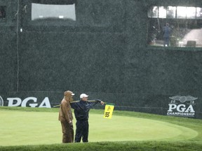 Members of the grounds crew stand on the 18th green during a weather delay in the third round of the PGA Championship at Baltusrol Golf Club in Springfield, N.J., on Saturday.