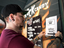 Jeff Powers, assistant manager at Rock Candy Boutique, puts up a sign encouraging Pokemon Go players to play inside the store in Halifax.