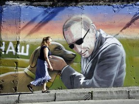 A woman walks by a mural depicting Russian President Vladimir Putin in the Crimean city of Yalta.