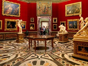 Visitors peek through a doorway at the Tribuna of the Uffizi, a domed octagonal room displaying paintings and statues in Florence, Italy.