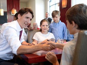 Prime Minister Justin Trudeau shakes hands with Russell Scarrow as Charlotte and James Farther look on during a visit to a restaurant in Aylmer, Que., on Wednesday, July 20, 2016.