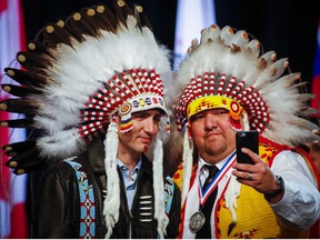 Prime Minister Justin Trudeau poses for a selfie with an elder after receiving a ceremonial headdress while visiting the Tsuut'ina First Nation near Calgary, Alta..