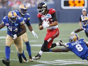 Calgary Stampeders receiver Anthony Parker jumps between Winnipeg Blue Bombers DL Euclid Cummings, left and Chris Randle during CFL action in Winnipeg on Thursday.