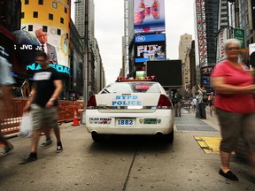 People walk by a New York Police Department (NYPD) car in Times Square