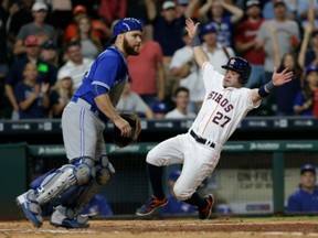 Jose Altuve of the Houston Astros slides behind Russell Martin of the Toronto Blue Jays to score the winning run in the fourteenth inning at Minute Maid Park on Monday in Houston, Texas.