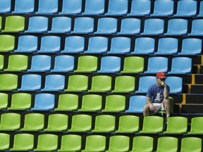 A fan sits surround by empty seats at the equestrian eventing dressage competition at the 2016 Summer Olympics in Rio de Janeiro, Brazil on Sunday, Aug. 7, 2016.