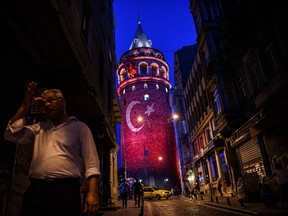 A man walks on a street near the Galata Tower, illuminated in Turkish flag colors on August 1,2016 at Galata district in Istanbul. Days after a coup attempt.