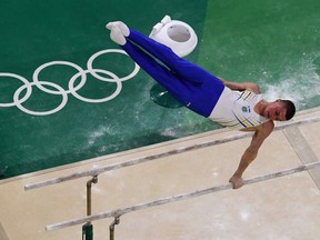 An overview shows Ukraine's Maksym Semiankiv competing in the qualifying for the men's horizontal bar event of the Artistic Gymnastics. Semiankiv went to the high bar in the final but hung on for a brief moment, then dropped and nodded toward the judges, apparently indicating an injury.