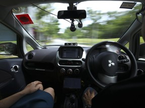 A driver, right, gets his hands off of the steering wheel of an autonomous vehicle during its test drive in Singapore Wednesday, Aug. 24, 2016.