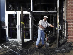 A city of Milwaukee employee cleans up a gutted Jet Beauty Supply, which was destroyed by fire and looting, in Milwaukee on Sunday, Aug. 14, 2016.
