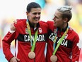 Canada captain Christine Sinclair, left, celebrates on the podium with teammate Sophie Schmidt.