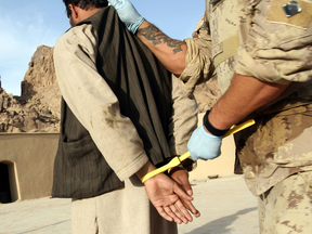 A suspected Taliban prisoner is searched, handcuffed, and processed by Canadian soldiers after a raid on a compound in Northern Kandahar, in 2006.
