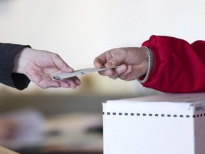 An election official hands back a marked ballot for the federal election in Toronto on May 2, 2011.