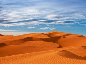 Sand dunes near the Morocco-Algeria border in the Sahara Desert are gracefully carved into ever-changing patterns by the winds and the dust they carry.