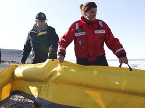 Prime Minister Stephen Harper helps deploy a boom on August 25, 2010 in Resolute Bay, Nunavut, during a mock oil spill in operation Nanook.