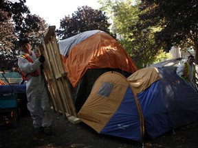 Workers from a hazmat company dismantle vacant tents remaining at tent city on the court house lawn in Victoria, B.C., Monday, August 8, 2016. The homeless camp outside Victoria's courthouse is now shut down.The provincial government says homes have been provided or offered to all the campers at the site and the tent city has been closed, in accordance with a court order issued in July.