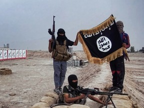 Islamic State militants post with the ISIL flag after allegedly seizing an Iraqi army checkpoint in 2014