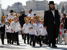 Ultra-Orthodox Jewish children and their rabbi go the Western Wall to celebrate a prayer book ceremony in the Old City of Jerusalem on July 12.