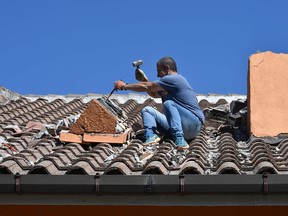 A man cleans the rubble from the slightly damaged roof of his house near the central Italian village of Amatrice, on August 28, 2016, four days after a 6.2-magnitude earthquake struck the region