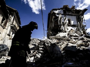 A firefighter inspects a collapsed house in Arquata, central Italy, Thursday, Aug. 25, 2016