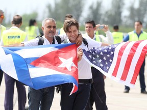 A father holding a Cuban flag, along with his son holding the American flag are seen on the tarmac after stepping off JetBlue's inaugural flight to Santa Clara, Cuba on Wednesday, Aug. 31, 2016.
