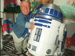 Kenny Baker, standing beside a replica of R2D2 from Star Wars at Planet Hollywood.