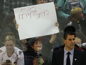 A young Lake Erie Monsters fan holds up his sign behind the Monsters bench with coach Jared Bednar early last season.