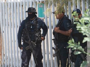 In this May 22, 2015, file photo, Mexican state police stand guard near the entrance of Rancho del Sol, where a shootout with the authorities and suspected criminals happened near Vista Hermosa, Mexico.
