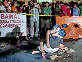Jennilyn Olayres cradles the body of her husband Michael Siaron after he was gunned down by vigilantes in a street in a rundown area of Manila'.