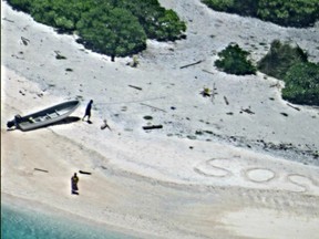 A pair of stranded mariners signal for help by writing "SOS" in the sand.