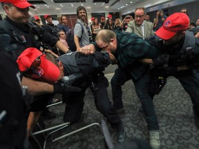 A protester scuffles with police while being removed from the National Energy Board public hearings into the Energy East pipeline in Montreal.