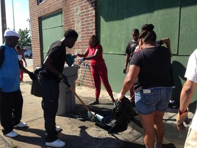 Volunteers sweep and pick up debris, Sunday, in a north Milwaukee neighbourhood that was rocked by hours of late-night violent unrest sparked by a police officer's shooting of a man fleeing a traffic stop.