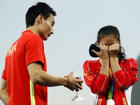 Silver medallist China's He Zi, covers her face in shock as she receives proposal during the podium ceremony of the Women's diving 3m springboard.