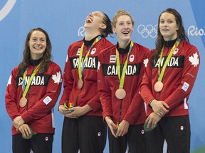 The Canadian women's 4x100m freestyle relay team members celebrate their bronze medal on the pool deck on Saturday night. From left, Sandrine Mainville, Chantal Van Landeghem, Taylor Ruck and Penny Oleksiak.