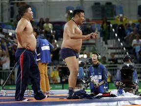 Coaches for Mongolia's Mandakhnaran Ganzorig strip in protest after a loss to Uzbekistan's Ikhtiyor Navruzov during the men's 65-kg freestyle bronze medal wrestling match at the 2016 Summer Olympics in Rio de Janeiro, Brazil, Saturday, Aug. 20, 2016.