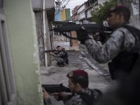 Brazil's national security force officers aim their weapons during a police operation in search for criminals in Vila do Joao, part of the Mare complex of slums during the Summer Olympics in Rio de Janeiro, Brazil, Thursday, Aug. 11, 2016.