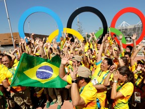 Volunteers cheer around a set of Olympic rings at the Olympic Park in Rio de Janeiro, Brazil, Monday, Aug. 1, 2016.