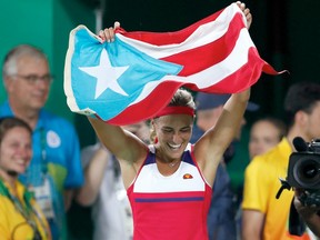 Monica Puig of Puerto Rico celebrates with her country's flag after winning women's tennis singles gold in Rio on Saturday.