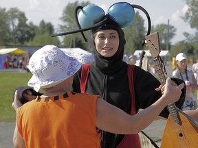 A woman dressed as a mosquito enjoys with others a sunny Sunday, Aug. 14, 2016, during the Russia Mosquito Festival in the town of Berezniki.