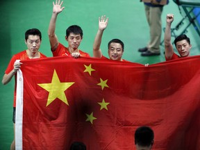 The Chinese Olympic men's tennis team celebrates their gold medal win over Japan.